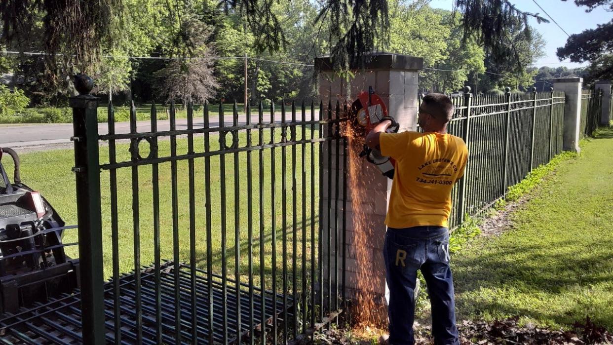 A worker cuts the wrought iron fence being replaced at Roselawn Memorial Park in LaSalle. Provided photo