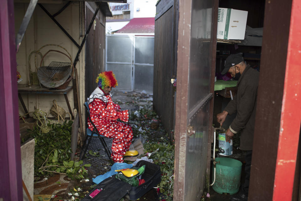 Belhussein Abdelsalam, a Charlie Chaplin impersonator puts on a clown outfit in a flower shop as he prepares to start a new day of work, in Rabat, Morocco, Thursday, Dec. 31, 2020. When 58-year-old Moroccan Belhussein Abdelsalam was arrested and lost his job three decades ago, he saw Charlie Chaplin on television and in that moment decided upon a new career: impersonating the British actor and silent movie maker remembered for his Little Tramp character. (AP Photo/Mosa'ab Elshamy)