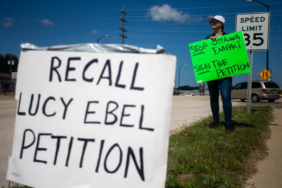 Sandra Hansen holds a sign calling for the recall of Ottawa County Commissioner Lucy Ebel in August 2023.