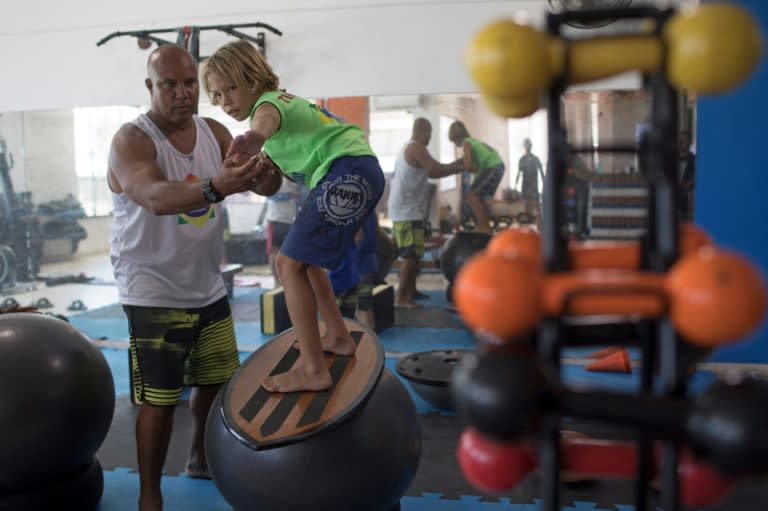 Luiz Augusto de Matos (R), 50, one of the teachers at "Saquarema Surf School", assists his pupil Miguel Cortinhas, 10, at the "Inside Fit" training center