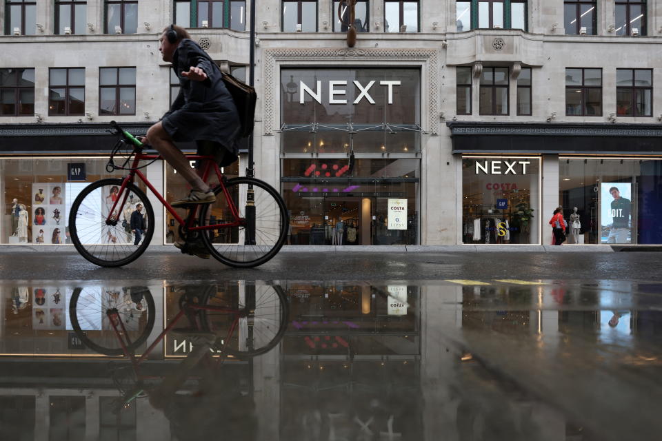 A cyclist rides past a Next store on Oxford Street in London, Britain, July 31, 2023. REUTERS/Hollie Adams