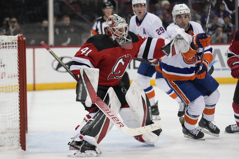 New Jersey Devils goaltender Vitek Vanecek, left, and New York Islanders' Kyle Palmieri, right, track the puck during the first period of an NHL hockey game in Newark, N.J., Tuesday, Nov. 28, 2023. (AP Photo/Seth Wenig)