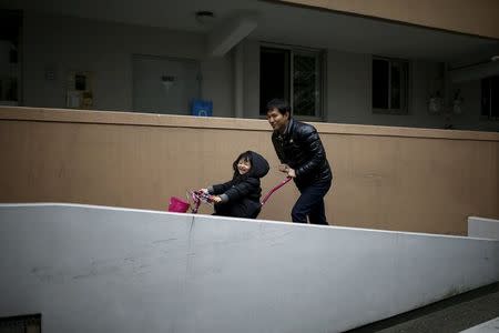 Chung Sang-hoon pushes his daughter's bicycle outside his apartment in Seoul, South Korea, December 14, 2015. REUTERS/Kim Hong-Ji