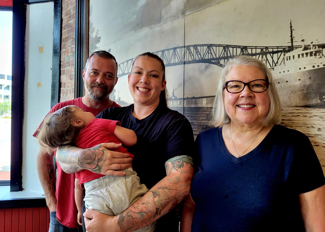 Belle River Winery owners Rob and Hannah Cowan, holding 17-month-old son Oliver, and Hannah's mother Michelle Burke share a moment on Friday, Sept. 22, 2023, in the downtown Port Huron space where they plan to open a tasting room.