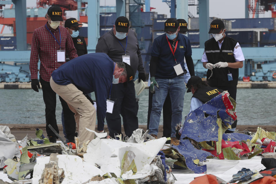 Members of the Indonesian National Transportation Safety Committee (KNKT) and U.S. National Transportation Safety Board (NTSB) investigators team inspect debris found in the waters around the location where a Sriwijaya Air passenger jet crashed, at the search and rescue command center at Tanjung Priok Port in Jakarta, Indonesia, Saturday, Jan. 16, 2021. (AP Photo/Achmad Ibrahim)