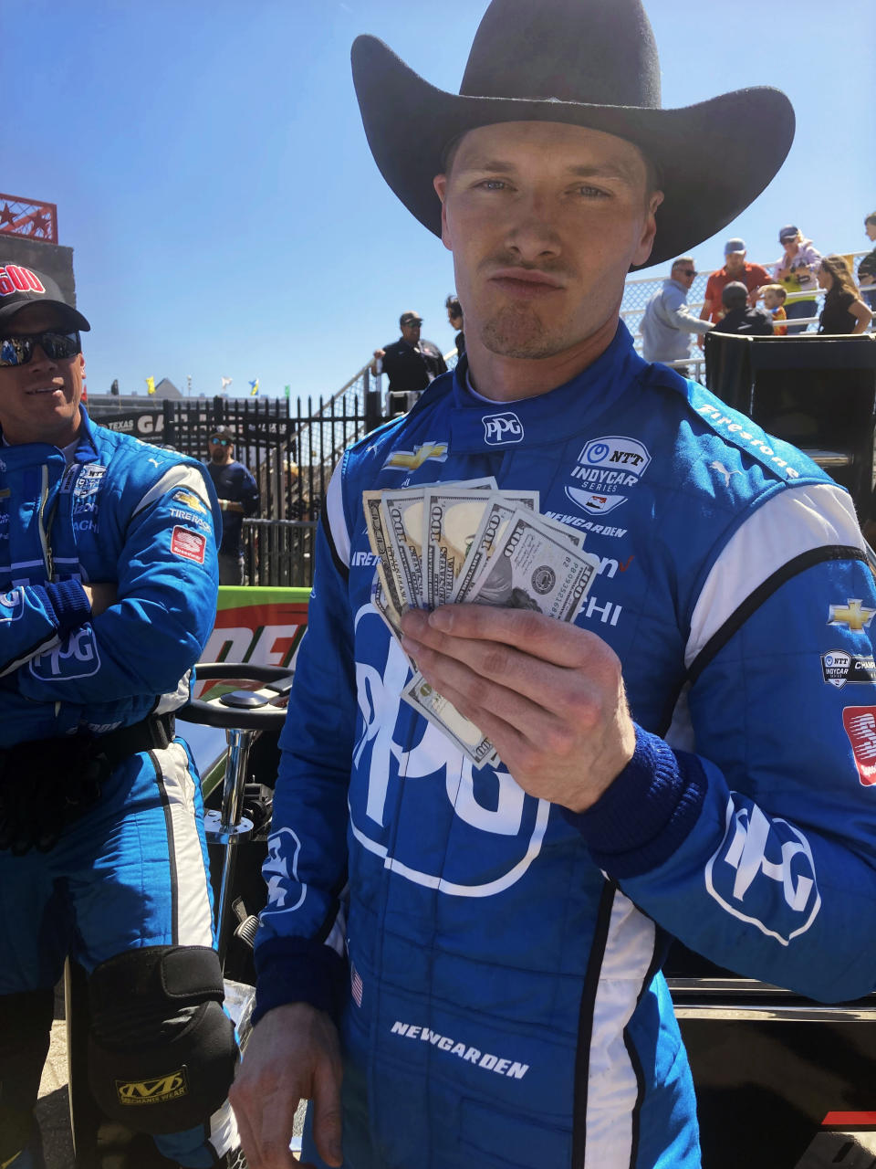 Josef Newgarden shows the $600 bonus that Roger Penske paid him in Victory Lane at Texas Motor Speedway in Fort Worth, Texas, after Newgarden won the 600th race in Team Penske history, Sunday, March 20, 2022. (AP Photo/Jenna Fryer)