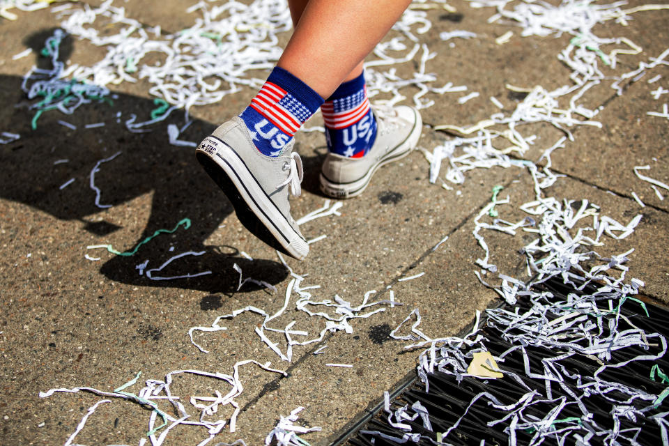 A person walks along the parade route as ticker tape litters the ground.&nbsp; (Photo: Demetrius Freeman for HuffPost)