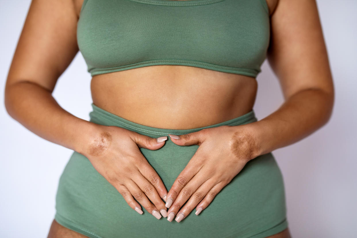 Woman with both hands placed on her stomach