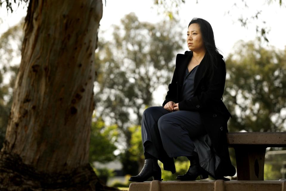 A woman sits on a picnic table at a park