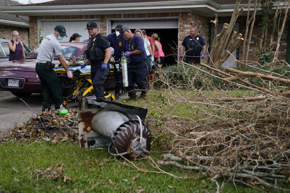 Paramedic J.T. Lebouef of Acadian Ambulance service, left, and others move a patient to an ambulance at a home damaged by Hurricane Ida, Friday, Sept. 3, 2021, in Houma, La. (AP Photo/John Locher)