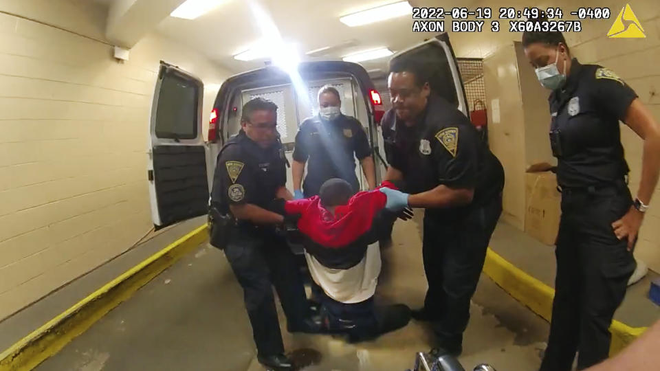 FILE - In this image taken from police body camera video provided by New Haven Police, Richard Cox, center, is placed in a wheelchair after being pulled from the back of a police van after being detained by New Haven Police, June 19, 2022, in New Haven, Conn. Five Connecticut police officers pleaded not guilty Wednesday, Jan. 11, 2023, to charges accusing them of cruelly mistreating Cox, a Black man, after he was partially paralyzed in a police van with no seat belts when the driver braked hard. (New Haven Police via AP, File)
