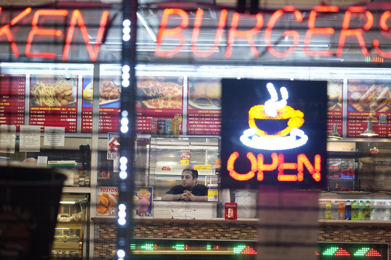 An employee of a restaurant waits for customers in an area where coronavirus cases have recently spiked in Newark, N.J., Thursday, Nov. 12, 2020. Nonessential businesses in Newark already must close at 8 p.m. and restaurant and bars must cease indoor service at 8 p.m., under an executive order signed by the mayor two weeks ago. In some parts of New Jersey's largest city residents are facing a 9 p.m. curfew for at least the rest of the month as officials seek to stop a surge in coronavirus infections. (AP Photo/Seth Wenig)