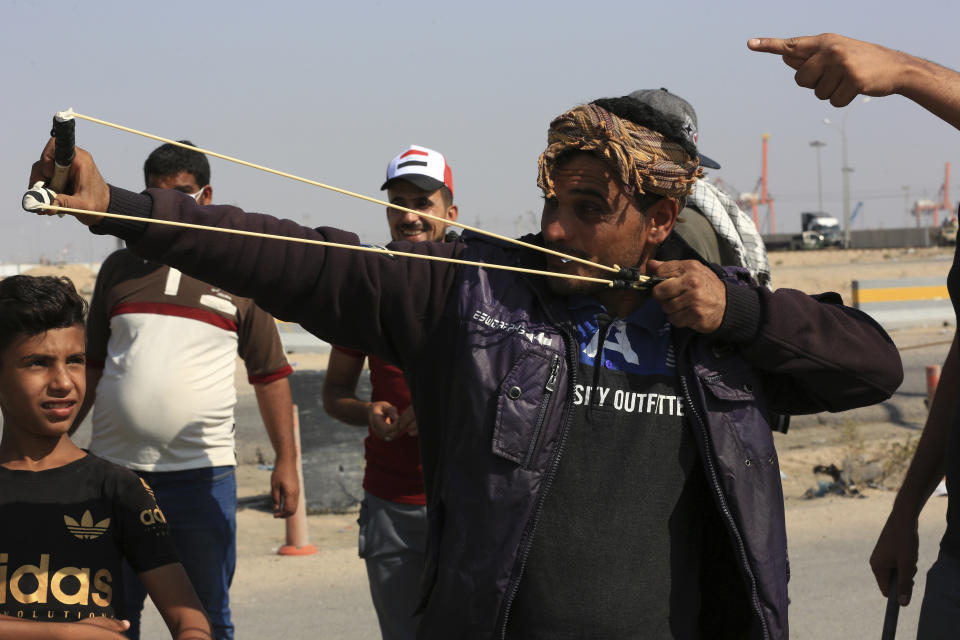 An anti-government protester fires a slingshot as they block the port of Umm Qasr during ongoing anti-government protests, in Basra, Iraq, Sunday, Nov. 3, 2019. (AP Photo/Nabil al-Jourani)