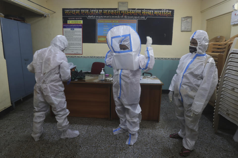 Health workers put on a protective suit before screening people for COVID-19 symptoms at a residential building in Dharavi, one of Asia's biggest slums, in Mumbai, India, Friday, Aug. 7, 2020. As India hit another grim milestone in the coronavirus pandemic on Friday, crossing 2 million cases and more than 41,000 deaths, community health volunteers went on strike complaining they were ill-equipped to respond to the wave of infection in rural areas. (AP Photo/Rafiq Maqbool)