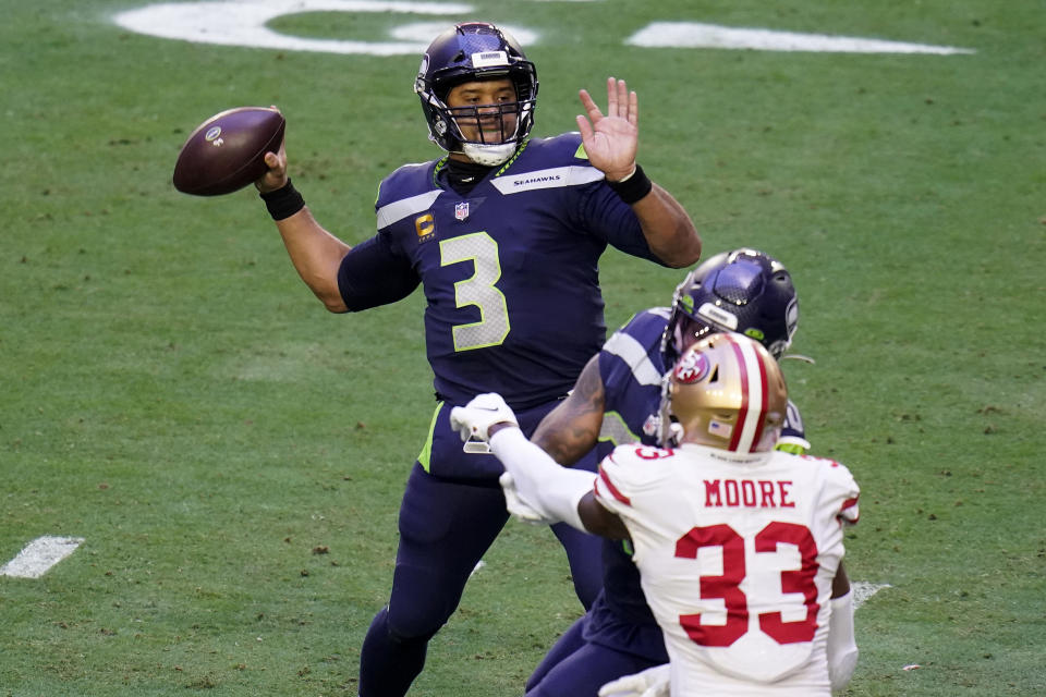 Seattle Seahawks quarterback Russell Wilson (3) shows as San Francisco 49ers defensive back Tarvarius Moore (33) pursues during the first half of an NFL football game, Sunday, Jan. 3, 2021, in Glendale, Ariz. (AP Photo/Ross D. Franklin)