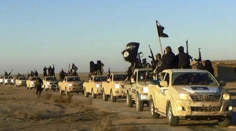 FILE - In this undated file photo released online in the summer of 2014 on a militant social media account, which has been verified and is consistent with other AP reporting, militants of the Islamic State group hold up their weapons and wave its flags on their vehicles in a convoy on a road leading to Iraq, in Raqqa, Syria. With Islamic State's near total defeat on the battle field, the extremist group has reverted to what it was before its spectacular series of conquests in 2014 _ a shadowy terror network that targets vulnerable civilian populations and exploits state weaknesses to incite on sectarian strife. But a recent surge in false claims of responsibility for attacks also signals that the group is struggling to stay relevant after losing its proto-state and its dominance of the international news agenda. (Militant photo via AP, File)