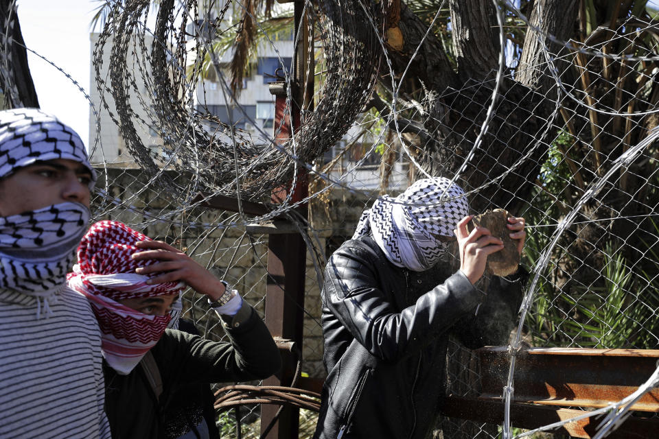 Protesters try to remove barbed wires that block a road leading to the U.S. embassy during a protest is held against the proposed peace deal for the Middle East by President Donald Trump, in Aukar, east of Beirut, Lebanon, Sunday, Feb. 2, 2020. Hundreds of Lebanese and Palestinians demonstrated Sunday near the U.S. embassy in Lebanon in rejection to a White House plan for ending the Israeli-Palestinian conflict. (AP Photo/Hassan Ammar)