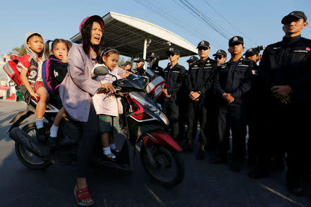 A woman rides a motorbike with children while Thai police block the street in front of the gate of Dhammakaya temple in Pathum Thani province, Thailand February 16, 2017. REUTERS/Jorge Silva