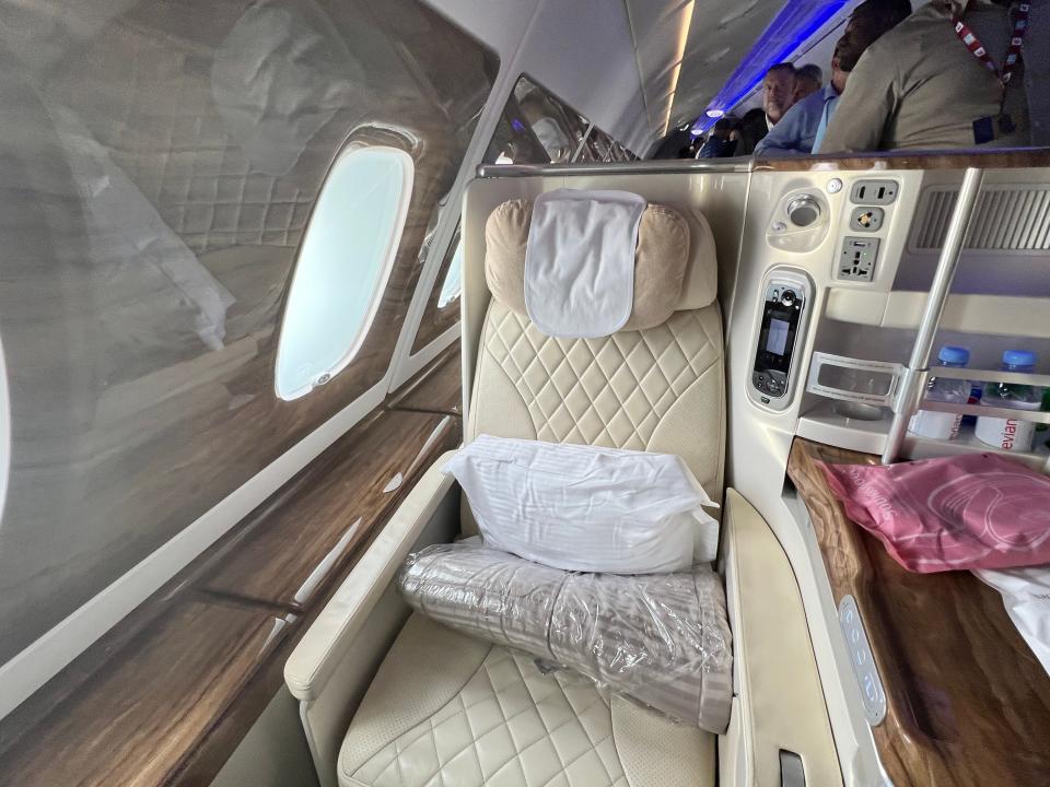 A window seat on Emirates A380 business class has beige leather, and dark wooden panels with storage compartment