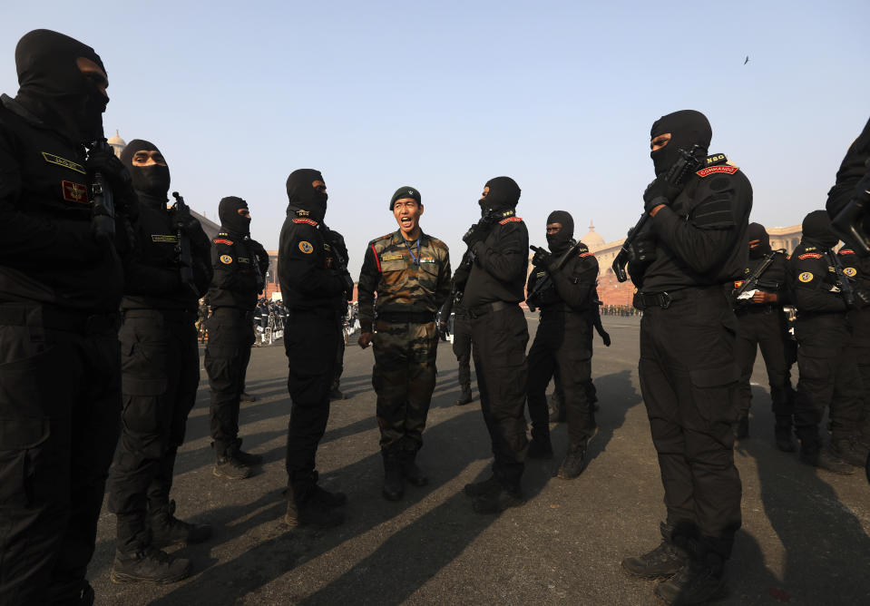 An instructor of National Security Guard watches as his colleagues prepare for a parade for the upcoming Republic Day parade in New Delhi, India, Thursday, Jan. 21, 2021. Republic Day marks the anniversary of the adoption of the country's constitution on Jan. 26, 1950. Thousands congregate on Rajpath, a ceremonial boulevard in New Delhi, to watch a flamboyant display of the country’s military power and cultural diversity. (AP Photo/Manish Swarup)