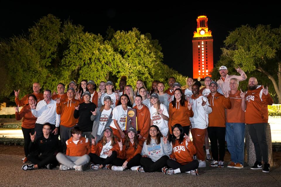 The Texas Longhorns volleyball team and support staff poses with the 2023 NCAA Volleyball Championship trophy in front of the UT Tower early on Monday, Dec. 18, 2023 in Austin.