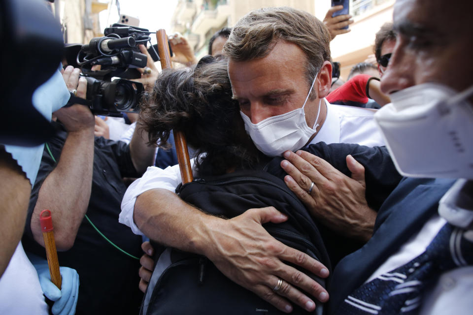 FILE - In this Aug. 6, 2020, file photo, French President Emmanuel Macron hugs a resident as he visits a devastated street of Beirut, Lebanon. In the wake of Beirut's massive port explosion, Macron has taken a tough line, setting deadlines for Lebanon's politicians to carry out reforms. His hands-on approach has angered some in Lebanon and brought praise from others. (AP Photo/Thibault Camus, Pool)