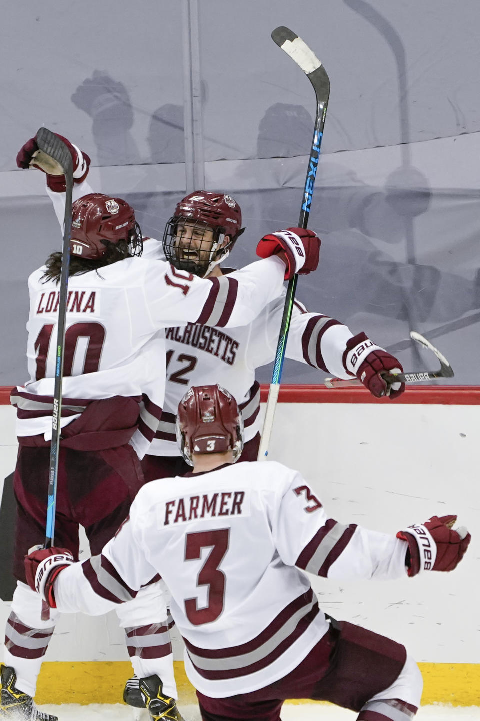 Massachusetts' Garrett Wait (12) celebrates with Josh Lopina (10) and Ty Farmer (3) after scoring in overtime against Minnesota Duluth in an NCAA men's Frozen Four hockey semifinal in Pittsburgh, early Friday, April 9, 2021. Massachusetts won 3-2 and will face St. Cloud State in the championship game Saturday. (AP Photo/Keith Srakocic)