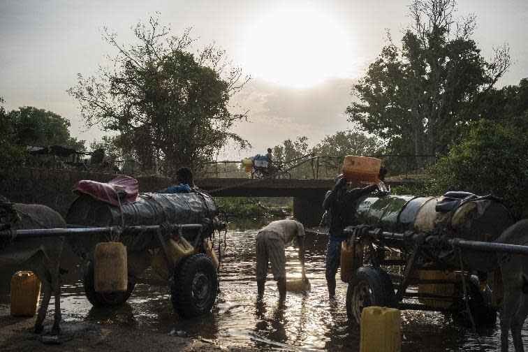 In this photo taken Thursday, March 9, 2017, young men fill water tanks from a river to take back and sell in neighborhoods around Torit, in South Sudan. As World Water Day approaches on March 22, more than 5 million people in South Sudan, do not have access to safe, clean water, compounding the problems of famine and civil war, according to the UNICEF. (Mackenzie Knowles-Coursin/UNICEF via AP)