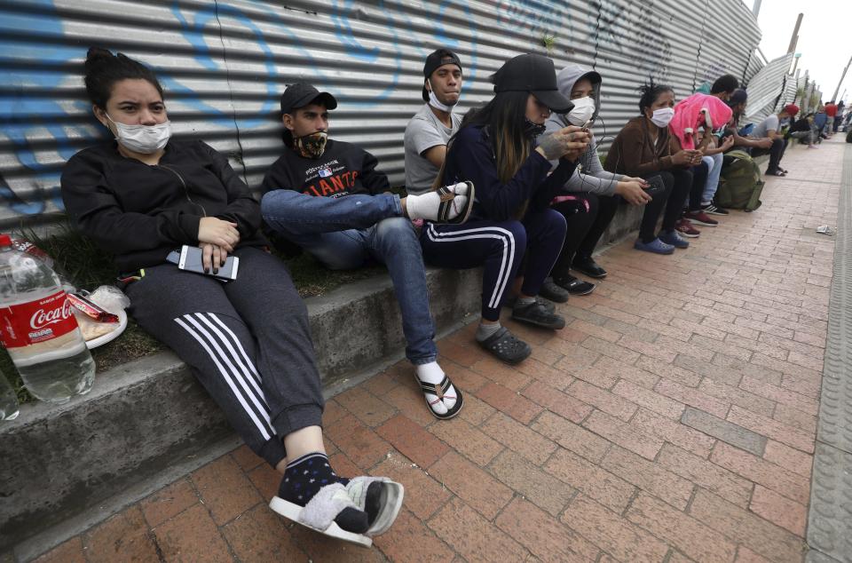 In this April 30, 2020 photo, Venezuelan migrants wait for buses that will transport them to the Venezuelan border, in Bogota, Colombia. The migrants want to return to their home country because they say they have not been able to find work in a country where businesses remain shuttered due to the new coronavirus pandemic and the strict stay-at-home order have limited their ability to help economically hurting relatives back home. (AP Photo/Fernando Vergara)