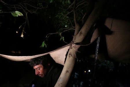 Joaquin, 36, a chef from Guatemala who says he was deported from the United States, sits underneath a tree near a section of the border fence separating Mexico and the United States, in Tijuana, Mexico. REUTERS/Edgard Garrido