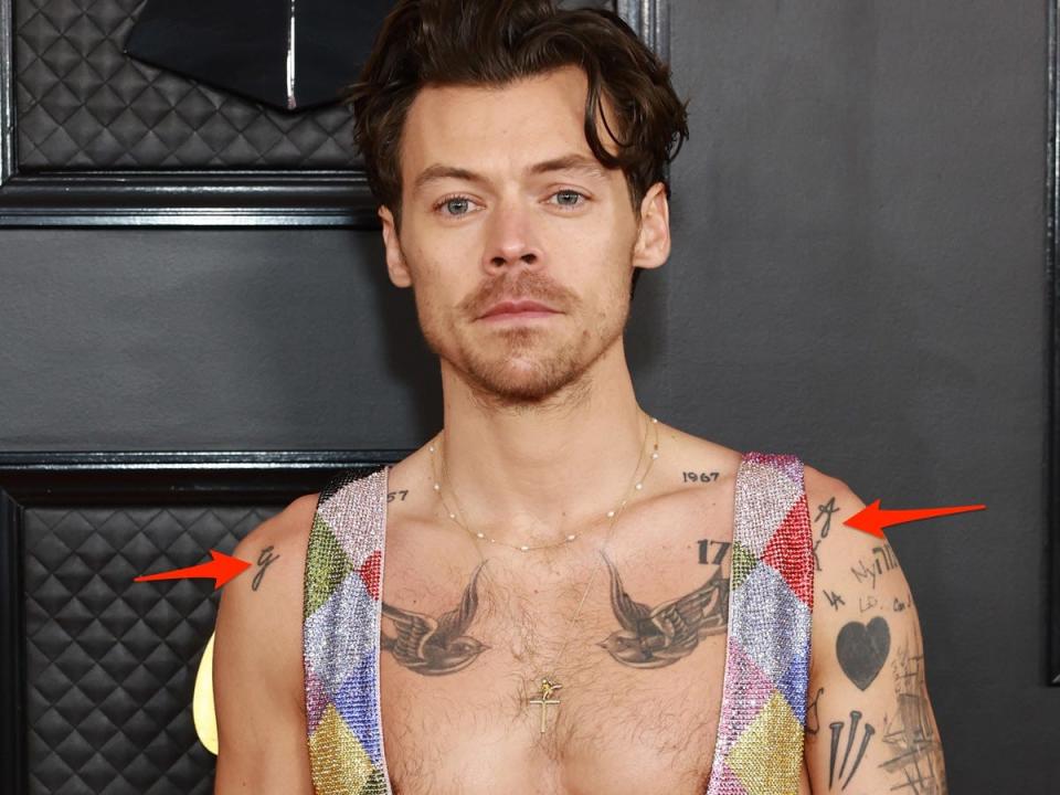 Red arrows pointing to tattoos on Harry Styles' shoulders.