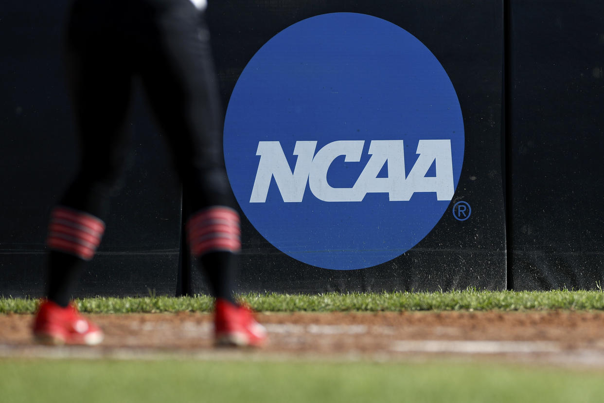 In this April 19, 2019, file photo, an athlete stands near a NCAA logo during a softball game in Beaumont, Texas. The NCAA is poised to take a significant step toward allowing college athletes to earn money without violating amateurism rules. The Board of Governors will be briefed Tuesday, Oct. 29 by administrators who have been examining whether it would be feasible to allow college athletes to profit of their names, images and likenesses. A California law set to take effect in 2023 would make it illegal for NCAA schools in the state to prevent athletes from signing personal endorsement deals. (AP Photo/Aaron M. Sprecher, File)