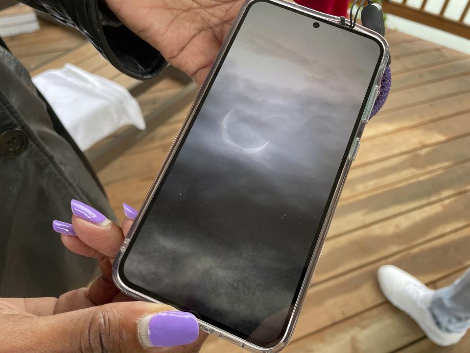 Crystal Marsh shows she took on her phone of the ring of fire eclipse in Eugene, Ore., on Saturday, Oct. 14, 2023. Totality of the annular eclipse was at times visible with the naked eye because of the cloud cover. Marsh drove five miles from Seattle with her family in order to be in the eclipse path. (AP Photo/Claire Rush)