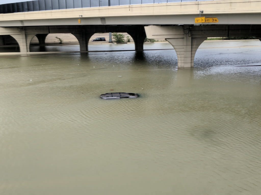 The roof of a submerged car is just barely visible beneath a bridge in Houston on Sunday.