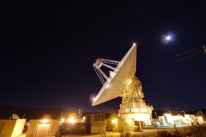 A massive antenna is lighted up against the night sky