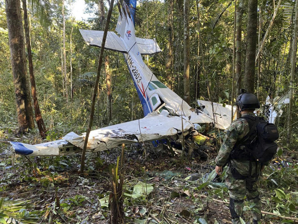 En esta foto proporcionada por la Oficina de Prensa de las Fuerzas Armadas de Colombia, un soldado permanece frente a los restos de una avioneta Cessna C206 el jueves 18 de mayo de 2023. La aeronave se estrelló en la selva de Solano, Colombia. Las autoridades buscan a cuatro niños indígenas quepiensan podrían haber sobrevivido el accidente. (Oficina de Prensa de las Fuerzas Armadas de Colombia, vía AP)