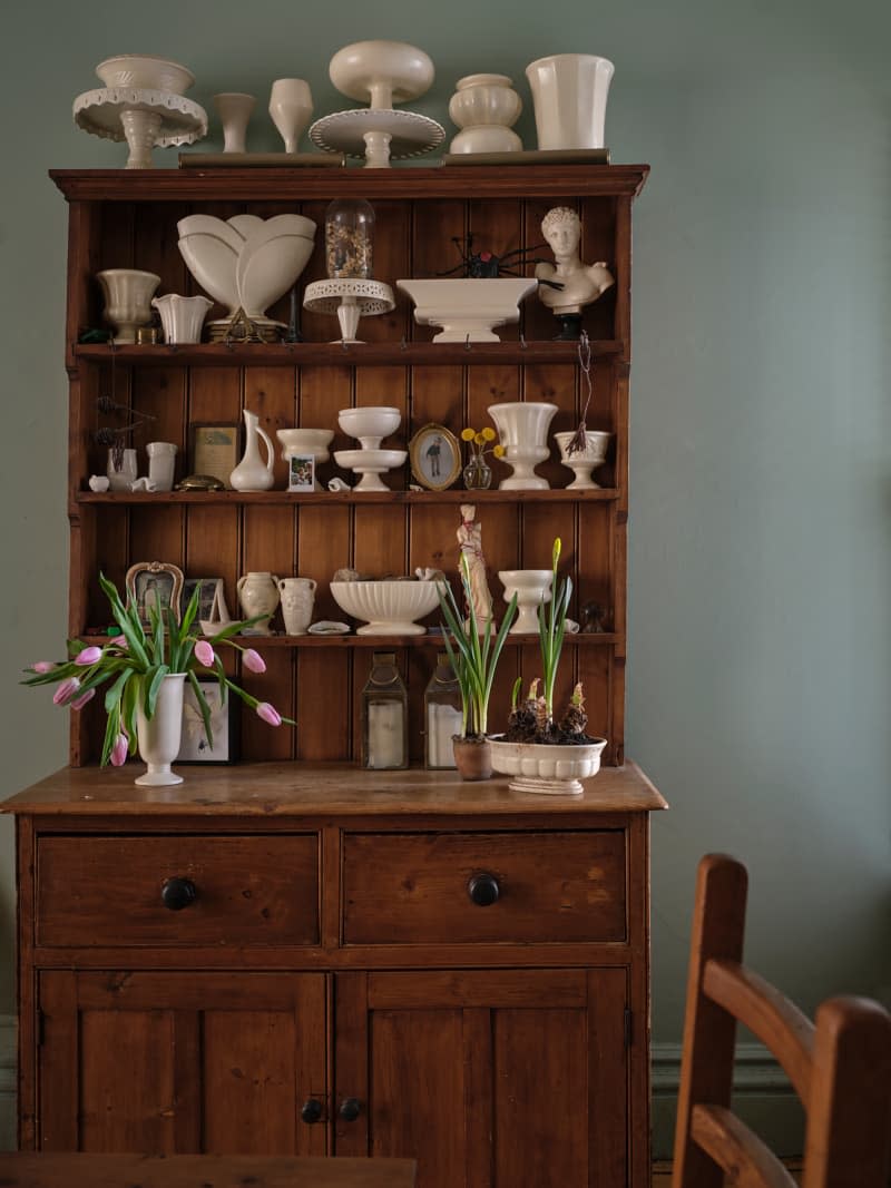 Cake stand, vases and planter collection on wooden cupboard.