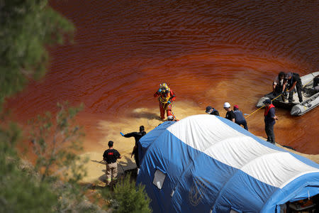 Police forensics officers, rescuers and divers retrieve a suitcase during an investigation for possible bodies of victims of a suspected serial killer in Kokkinopezoula lake, also known as "red lake", near the village of Mitsero, Cyprus, May 5, 2019. REUTERS/Yiannis Kourtoglou