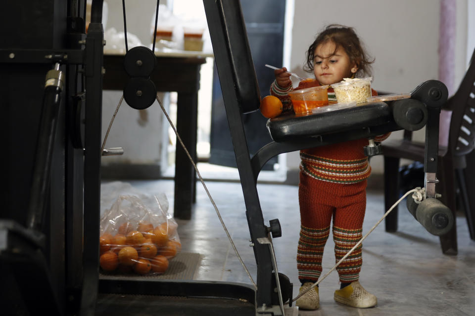 A displaced Syrian girl eats food given to her by a volunteer group inside a gymnasium being used as a homeless shelter following a devastating earthquake, in the coastal city of Latakia, Syria, Friday, Feb. 10, 2023. The 7.8 magnitude earthquake that hit Turkey and Syria, killing more than 23,000 this week has displaced millions of people in war-torn Syria. The country's 12-year-old uprising turned civil war had already displaced half the country's pre-war population of 23 million before the earthquake. (AP Photo/Omar Sanadiki)