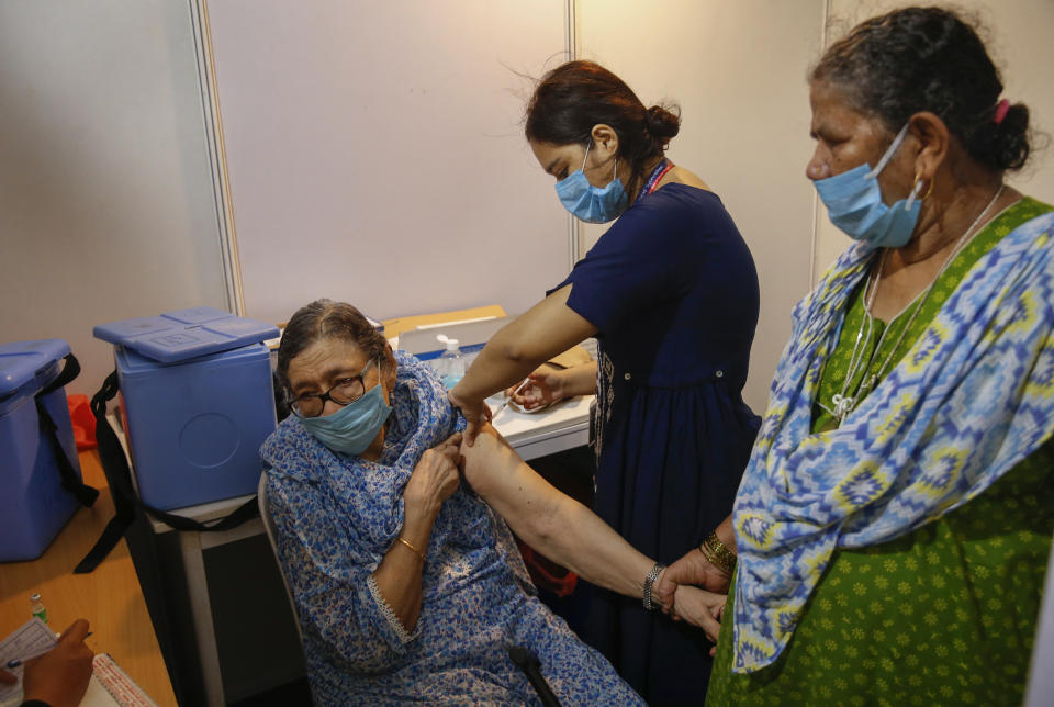 An elderly woman, left, holds the arm of her domestic helper as she receives Covishield vaccine against the coronavirus at a vaccination center in Mumbai, India, Tuesday, June 22, 2021. (AP Photo/Rafiq Maqbool)