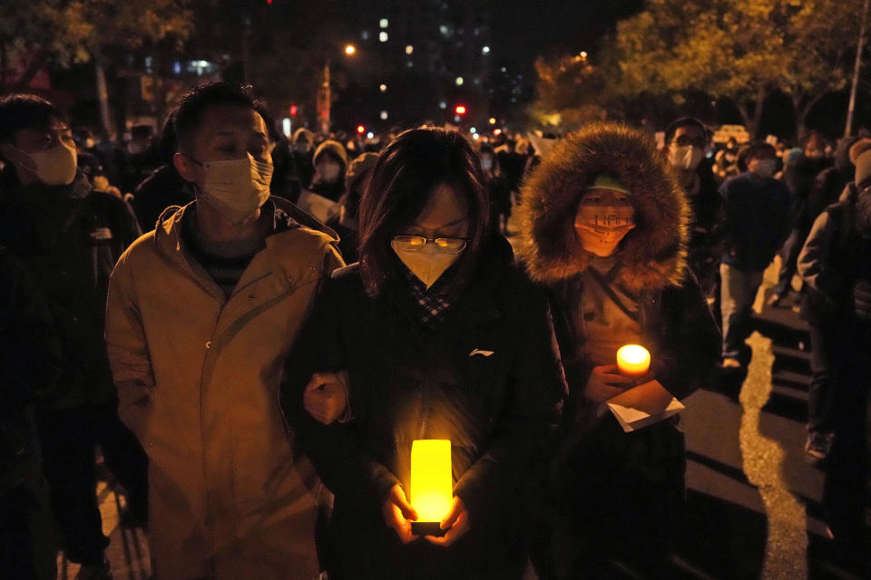 Protesters hold candles as they march in Beijing, Sunday, Nov. 27, 2022. Protesters angered by strict anti-virus measures called for China's powerful leader to resign, an unprecedented rebuke as authorities in at least eight cities struggled to suppress demonstrations Sunday that represent a rare direct challenge to the ruling Communist Party. (AP Photo/Ng Han Guan)