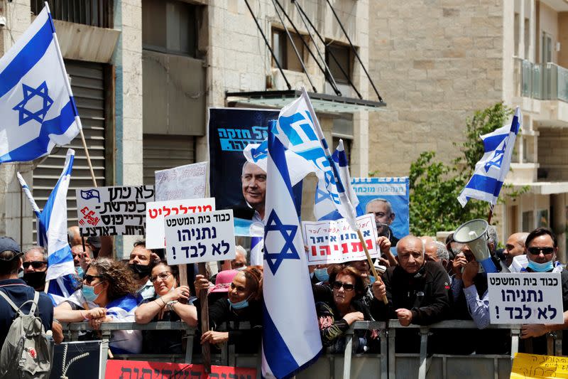 Supporters of Israeli Prime Minister Benjamin Netanyahu wave Israeli flags and hold placards as they rally just before Netanyahu's corruption trial opens, outside the District Court in Jerusalem