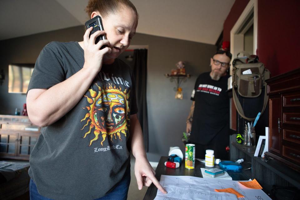 Amy Warix stands at the desk where she makes calls to advocate for her partner John's healthcare, Warner Springs, Calif., Sept. 30, 2021.