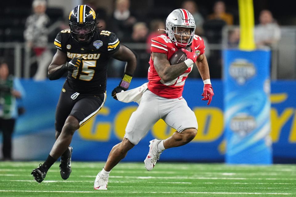 Dec 29, 2023; Arlington, Texas, USA; Ohio State Buckeyes running back TreVeyon Henderson (32) runs away from Missouri Tigers defensive lineman Johnny Walker Jr. (15) during the third quarter of the Goodyear Cotton Bowl Classic at AT&T Stadium. Ohio State lost 14-3.