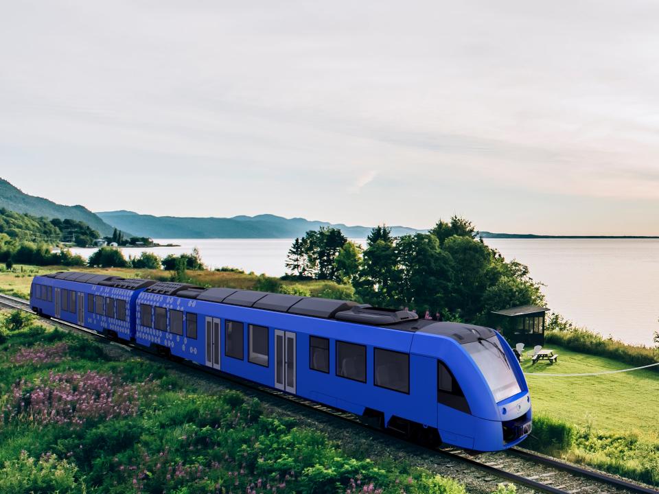 Rendering of a blue Coradia iLint hydrogen-powered train running along the St. Lawrence river in Quebec.