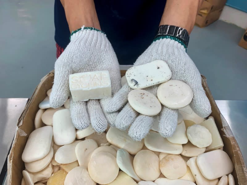 A staff member of Soap Cycling, a Hong Kong-based non-governmental organisation, shows used soap collected from hotels for recycling, and reprocessed soap, at their warehouse in Hong Kong