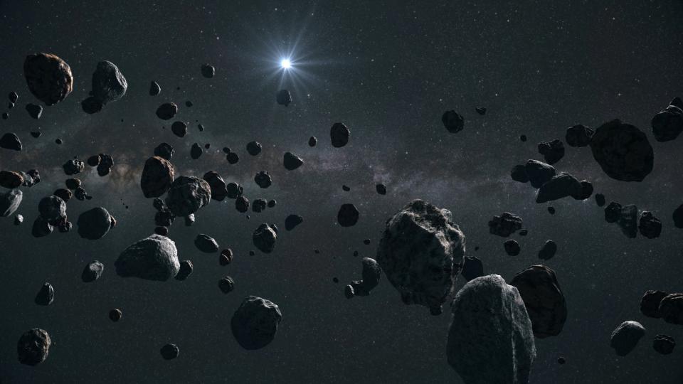 A large group of asteroids with the sun in the distance