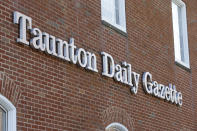 In this Monday, Aug. 5, 2019 photo a Taunton Daily Gazette sign is attached to the exterior of the newspaper's offices, in Taunton, Mass. The newspaper is published by GateHouse Media New England, a division of GateHouse Media Inc. On Monday, GateHouse Media, a chain backed by an investment firm, announced that it is buying USA Today owner Gannett Co. (AP Photo/Steven Senne)