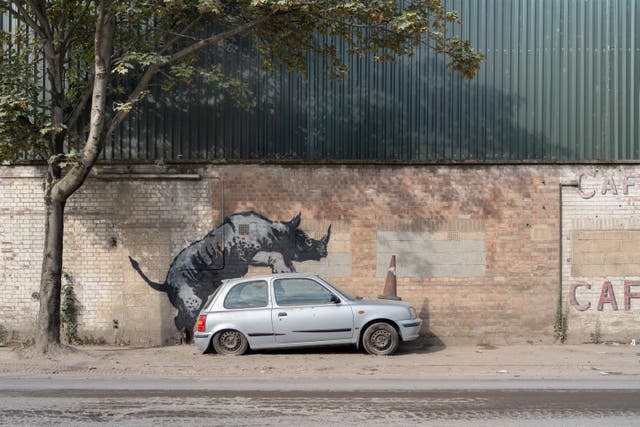 A Banksy artwork depicting a rhinoceros climbing on top of a car