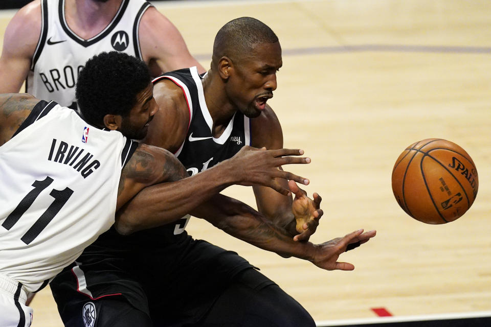 Brooklyn Nets guard Kyrie Irving, left, and Los Angeles Clippers center Serge Ibaka go after a rebound during the first half of an NBA basketball game Sunday, Feb. 21, 2021, in Los Angeles. (AP Photo/Mark J. Terrill)
